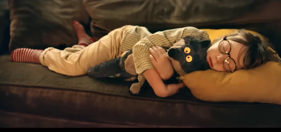 Enfant dort sur canapé avec la peluche du loup dans les bras